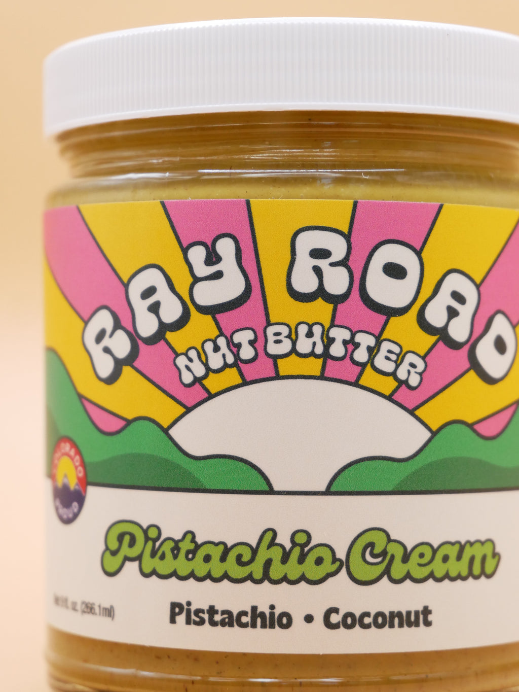 close up Jar of ray road nut butter pistachio cream with peach background