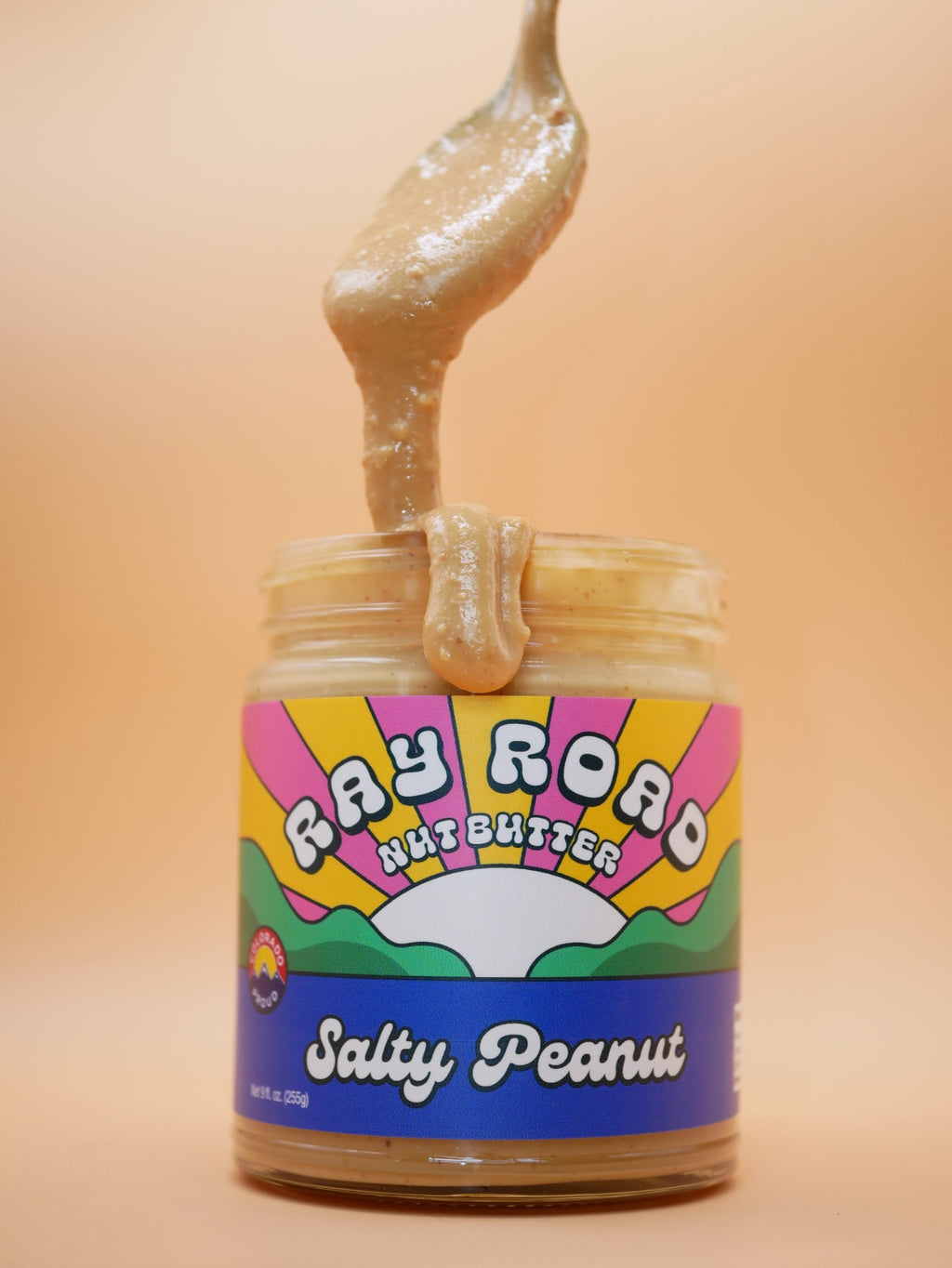 Spoonful of creamy Salty Peanut butter dripping into the jar