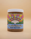 jar of ray road nut butter, sea salt vanilla flavor. ray road rainbow logo with blue. peach background
